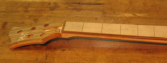 Zebra wood headstock and binding on a five string bass neck