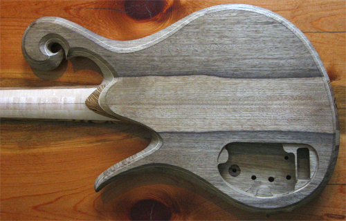 Back of the custom bass body and neck showing black limba book-match, bocote neck heel and electronics cavity.