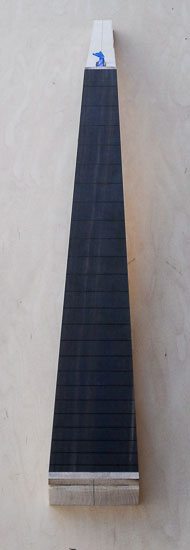Low angle shot of an ebony fretboard on a bass guitar neck blank