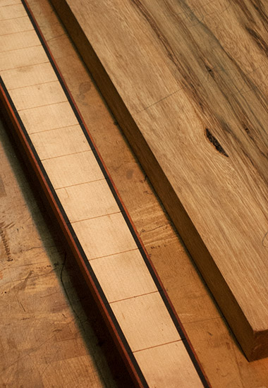 Custom bass neck with maple fretboard, ebony stringers, bloodwood binding