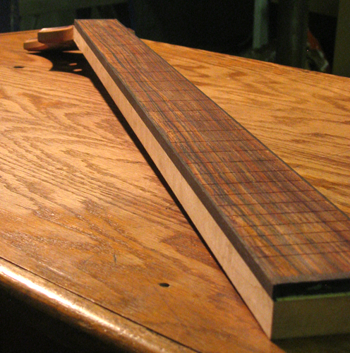 Ebony-bound cocobolo fingerboard of the bass guitar on the rock maple neck