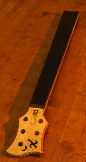 Curly maple headstock and ebony fretboard of a 5 string custom bass