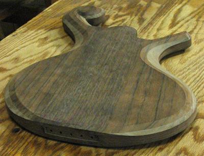 Back of the bass body from an angle showing the bookmatch of the old black walnut.