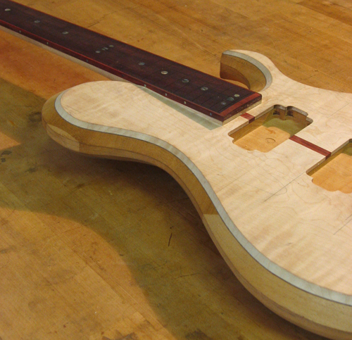 Flamed maple top of a custom guitar with black walnut veneer accent